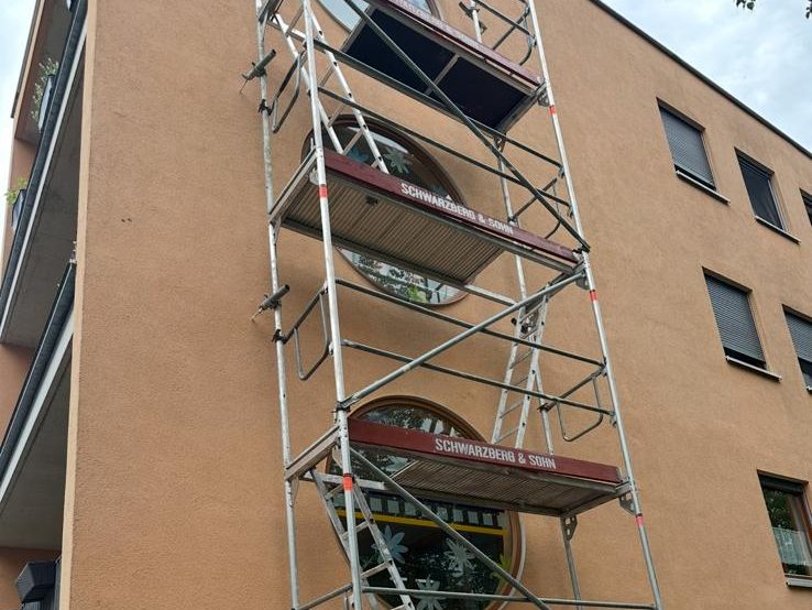 Gerüst über mehrere Stockwerke an einer verputzten Hausfassade